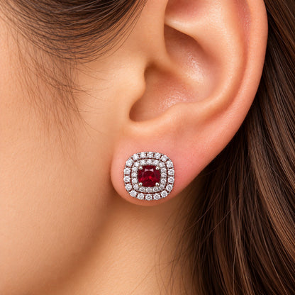 Close-up of a woman's ear wearing the Regent Cushion Zircon Stud in ruby red, highlighting its cushion-shaped design and clear zircon borders.