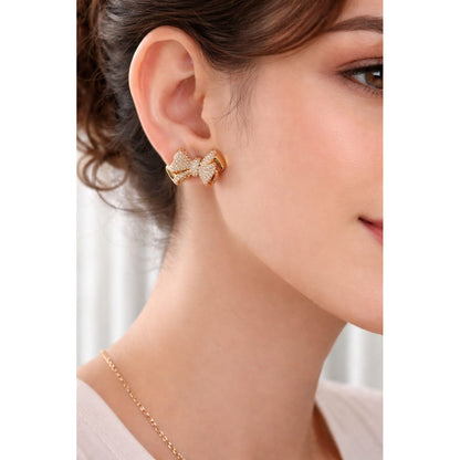 Gold bow stud earrings worn on model’s ear, close-up view showing true size, shine, and micro-pavé details.
