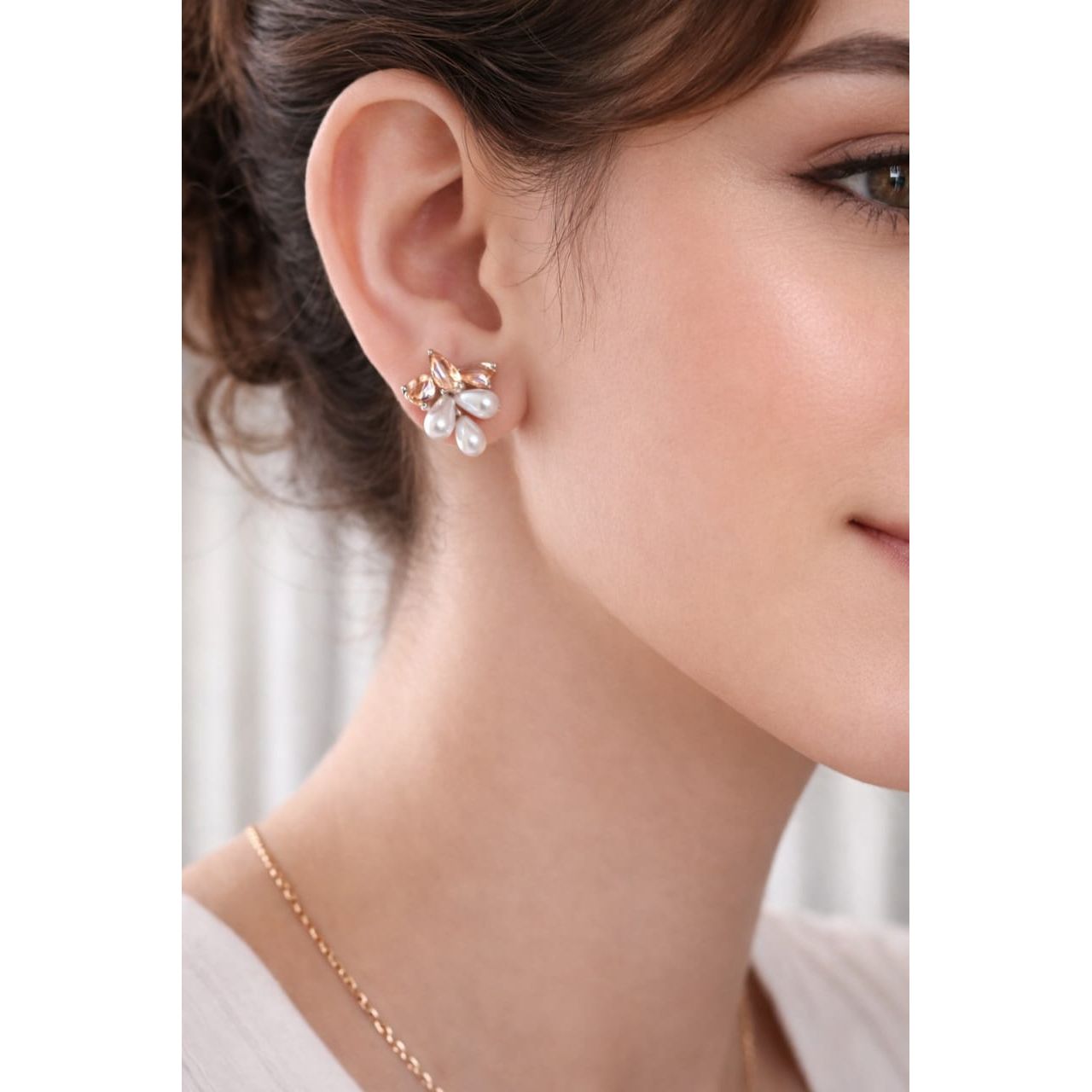 Creamy pearl cluster stud earrings with crystal petal design worn on model ear, close-up showing natural size and detailing.
