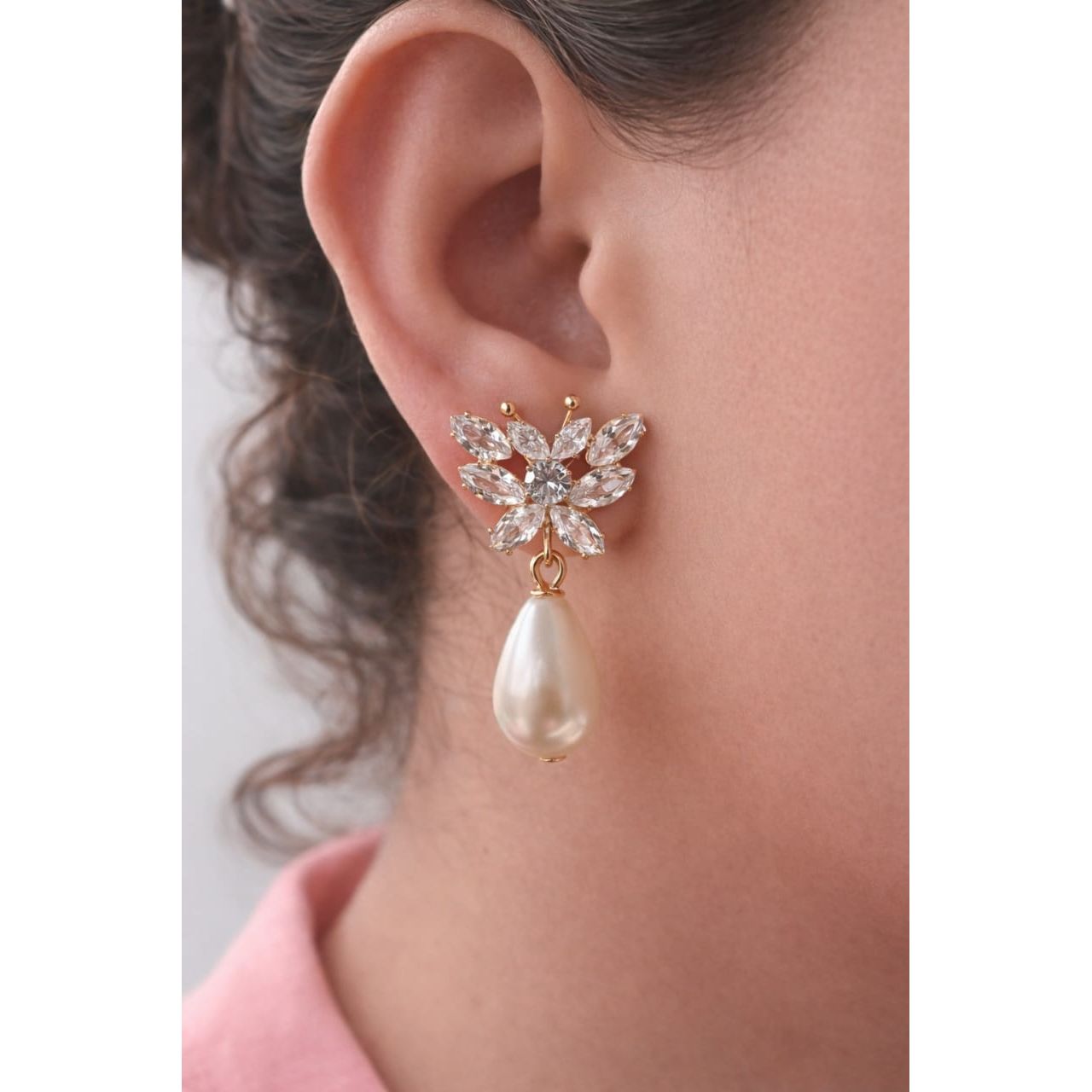 Gold butterfly crystal pearl drop earring on model ear side profile showing butterfly wing crystals and teardrop pearl detail