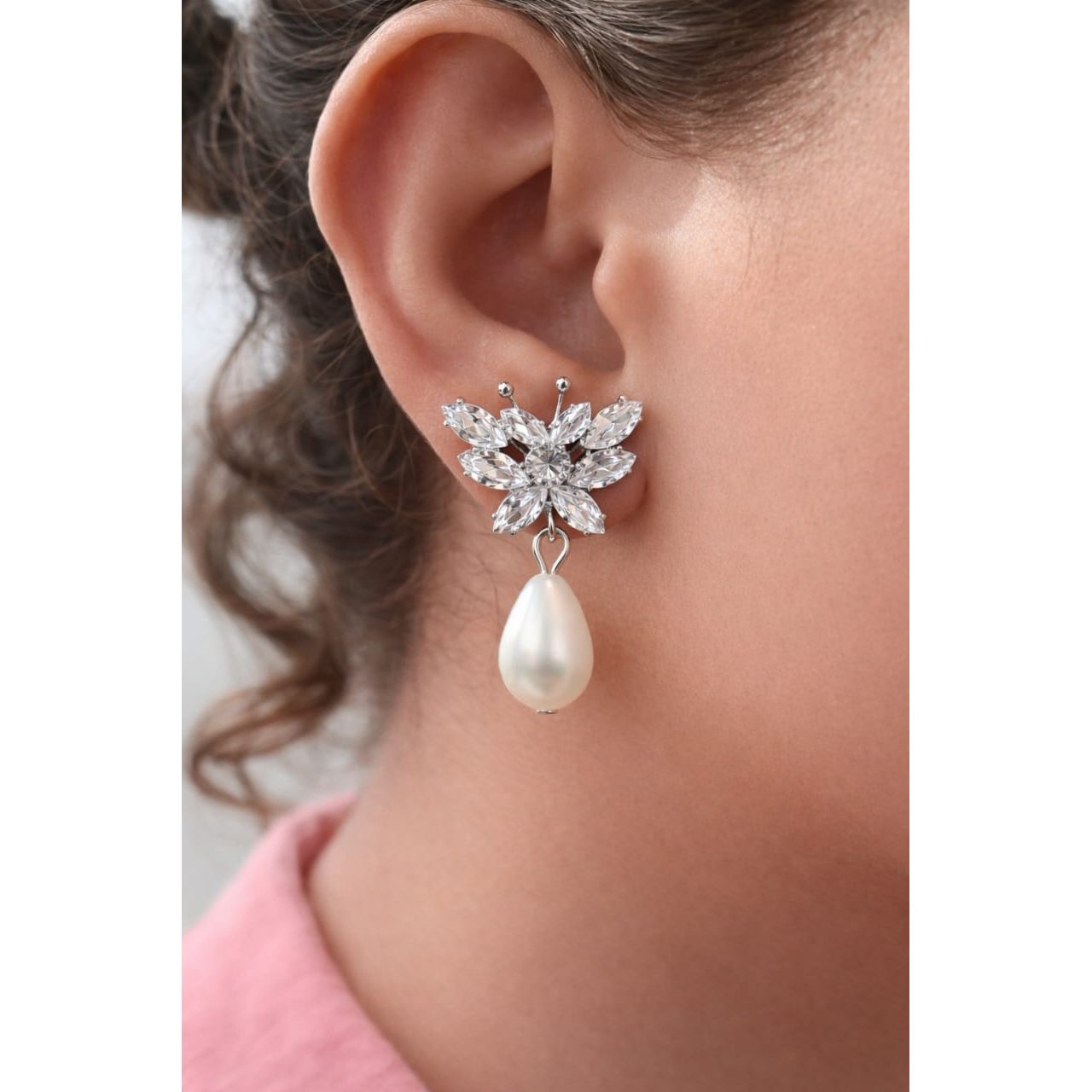 Silver butterfly crystal pearl drop earring worn on model ear close-up highlighting wing-shaped crystal arrangement and pearl drop