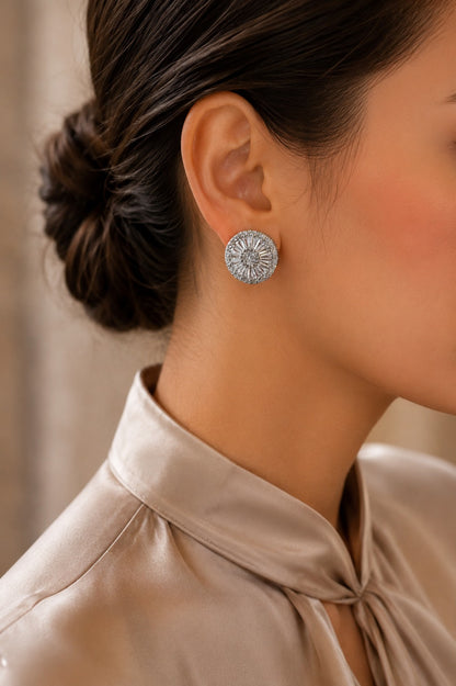 Model wearing radiant silver-tone halo crystal stud earrings with a circular sunburst design, styled with a champagne satin blouse for a refined everyday and occasion look.