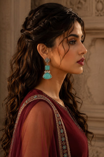 Woman wearing Legacy Collection antique mint green statement earrings with pearl detailing in a side profile.