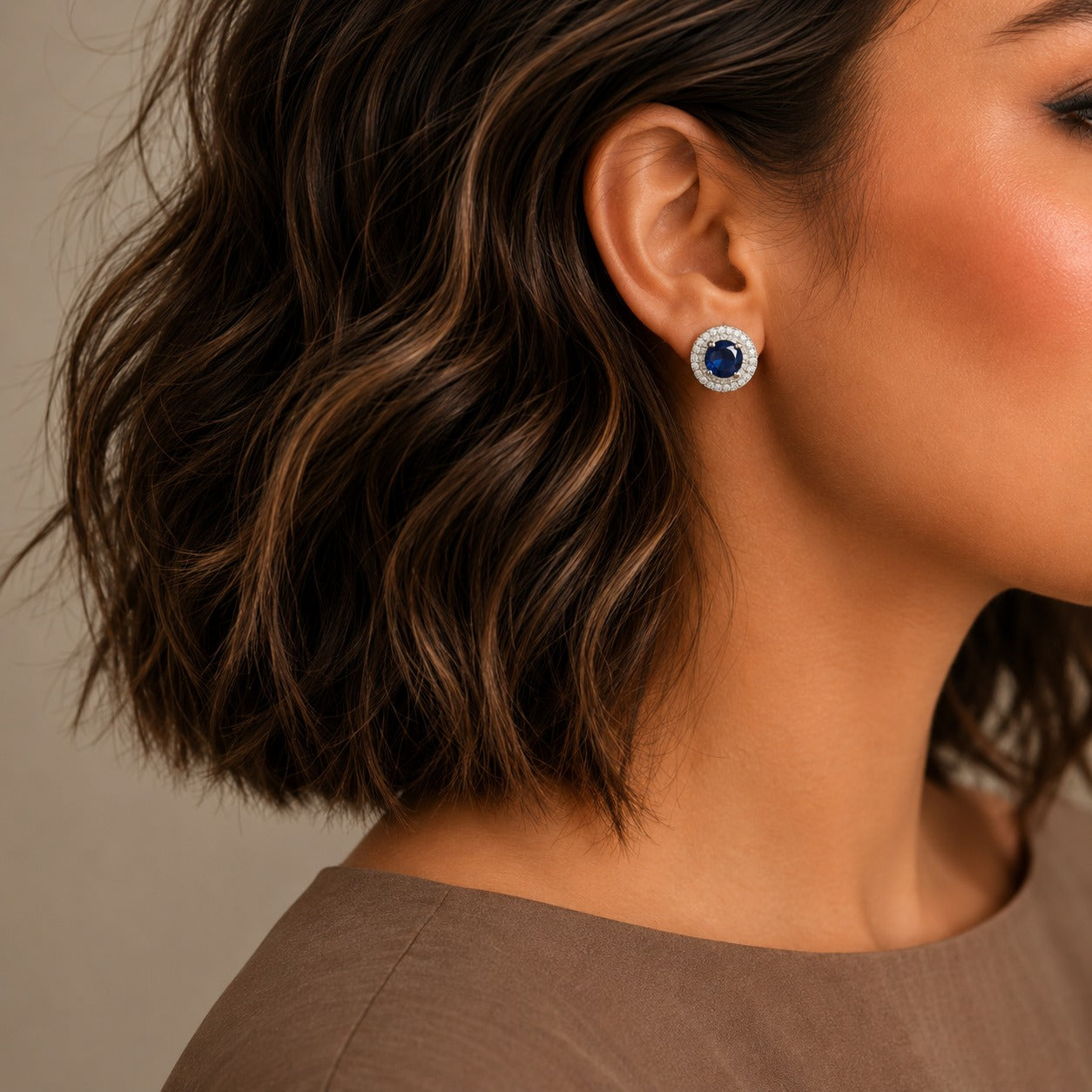 Royal blue halo gemstone stud earrings worn on model featuring sparkling crystal halo in silver-tone finish.