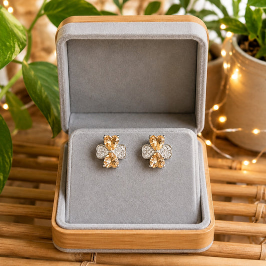 Silver crystal bow stud earrings featuring champagne heart-cut stones displayed in a premium grey velvet jewellery box.