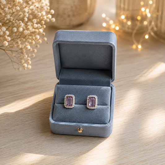 Lavender emerald-cut halo stud earrings displayed in a premium blue velvet jewellery box