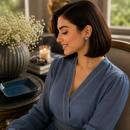 Woman wearing round blue crystal floral stud earrings in a side-profile portrait with focus on the earrings.