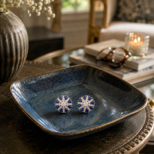Blue and crystal floral stud earrings displayed on a premium ceramic tray in a luxury home setting.