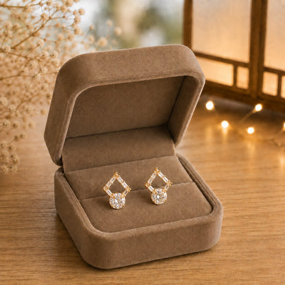 Golden geometric crystal drop earrings displayed inside a premium taupe velvet jewellery box with sparkling baguette-cut stones and brilliant round crystal  