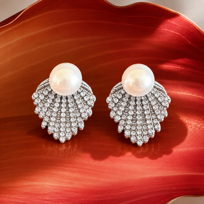 Close-up of silver-tone pearl earrings featuring a fan-shaped cascade of clear zircon stones beneath round white pearls.