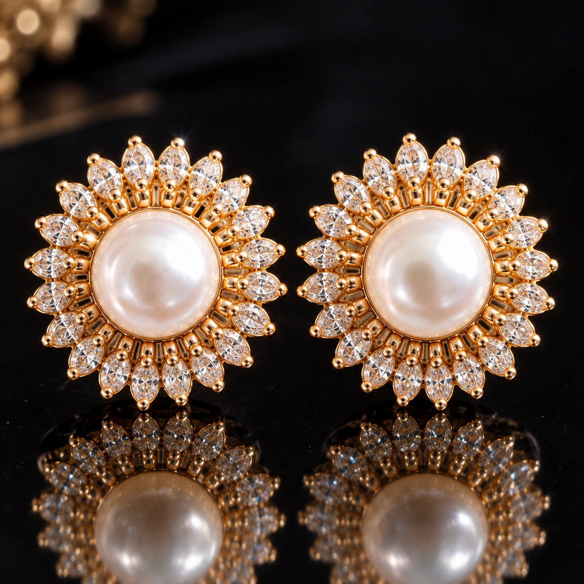  Close up of Pair of gold-tone Pearl Sunray Stud Earrings with round white pearl centres surrounded by radiating marquise-cut clear stones on a reflective black surfac