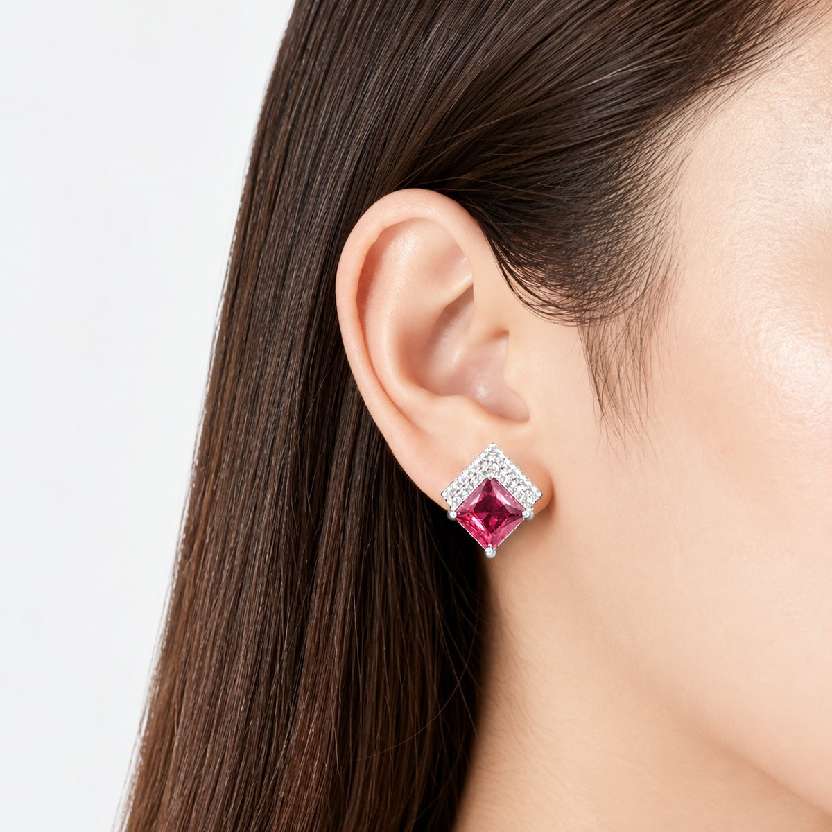 Close-up of geometric gemstone stud earring worn on the ear, featuring a princess-cut centre stone and clear zircon upper detailing.