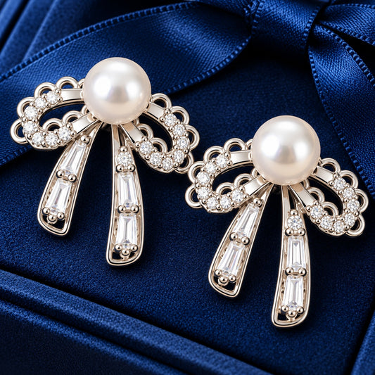 Silver-tone bow stud earrings with white pearl centres, clear zircon detailing and baguette-cut stone drops.