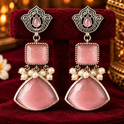 Heirloom Crest Drops in soft rose pink with silver-toned detailing and pearl accents, displayed on rich burgundy velvet.