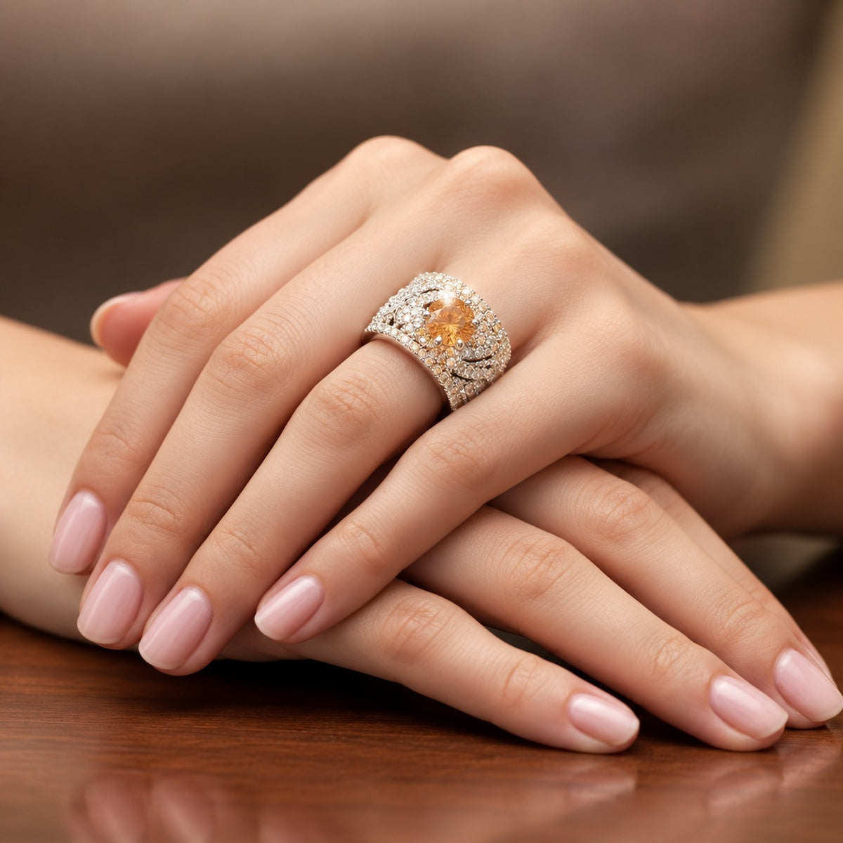 Amber Empress Zircon Ring worn on a woman's finger, featuring a vibrant amber-orange centre stone and an intricately detailed silver-tone band.