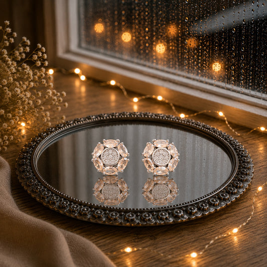 Floral crystal stud earrings with marquise-cut  beige gemstone petals and a sparkling pavé center displayed on a decorative mirrored tray in a luxury jewelry photography setting.
