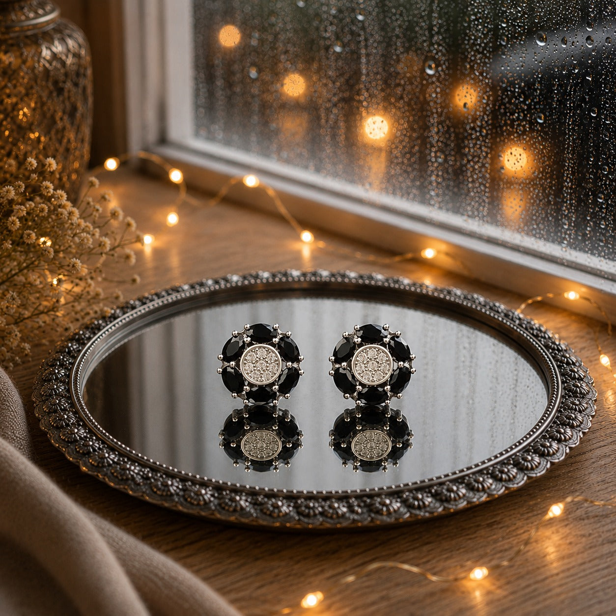Floral crystal stud earrings with marquise-cut  black gemstone petals and a sparkling pavé center displayed on a decorative mirrored tray in a luxury jewelry photography setting.