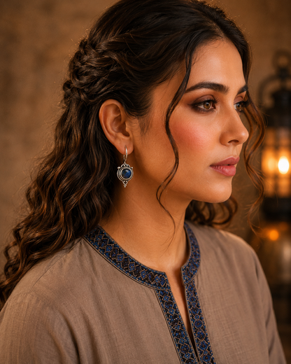 Woman wearing antique blue round gemstone drop earrings with vintage detailing and embroidered taupe kurta, side profile jewellery photography.
