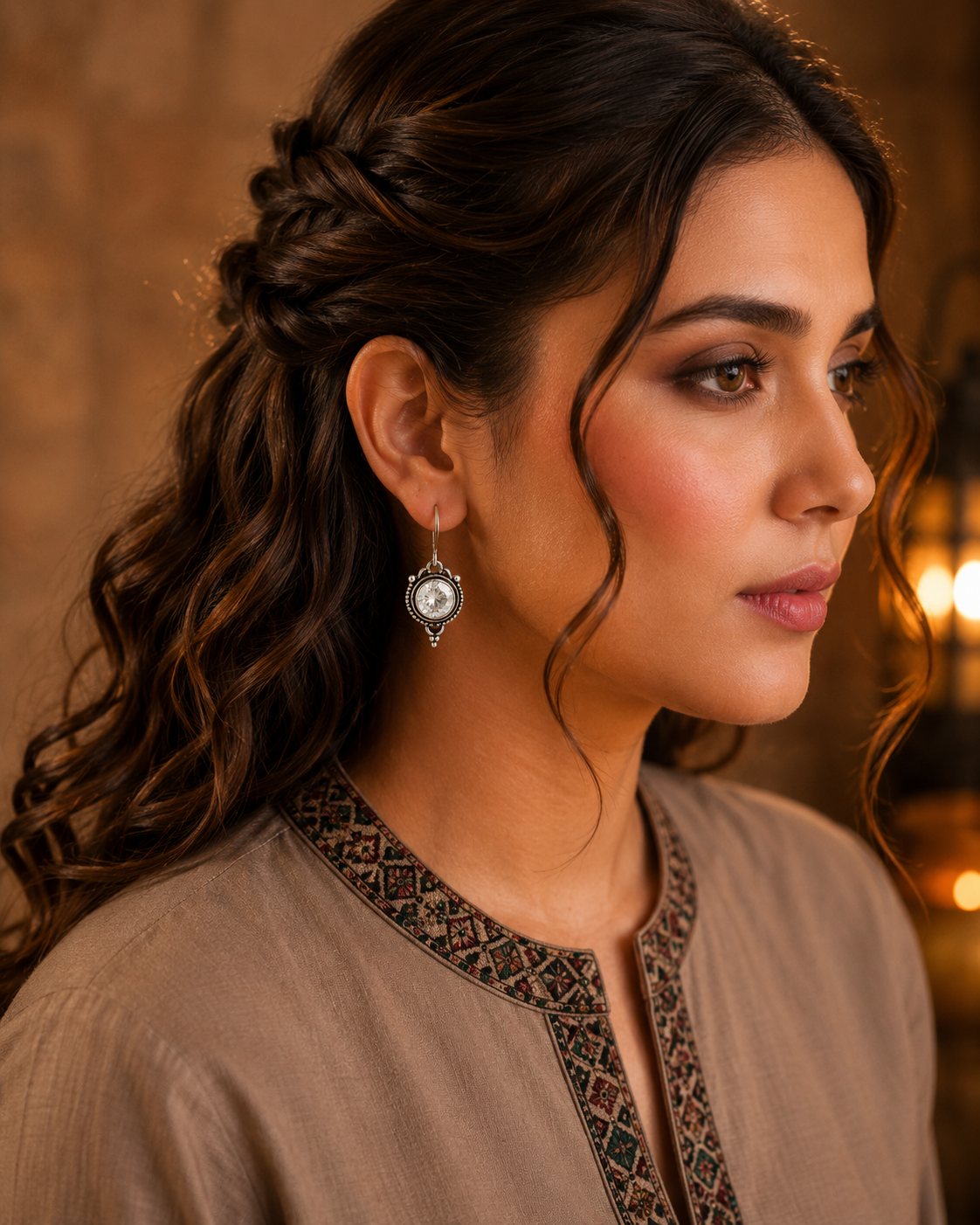 Woman wearing antique silver round gemstone drop earrings with vintage detailing and embroidered taupe kurta, side profile jewellery photography.