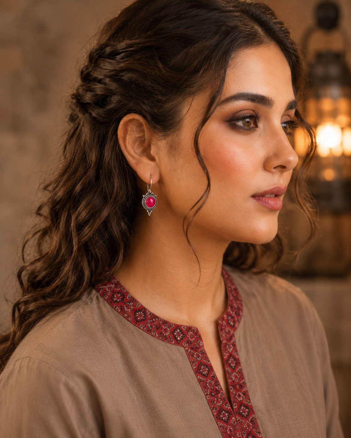 Woman wearing antique hot pink round gemstone drop earrings with vintage detailing and embroidered taupe kurta, side profile jewellery photography.