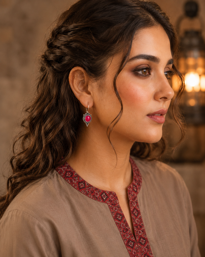 Woman wearing antique hot pink round gemstone drop earrings with vintage detailing and embroidered taupe kurta, side profile jewellery photography.