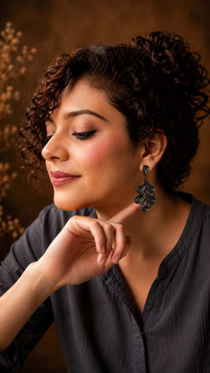 Woman with curly hair wearing black earrings against a warm brown background