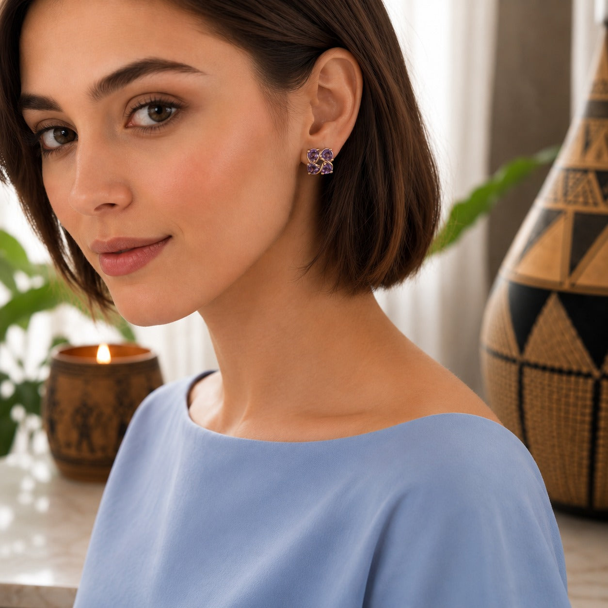 Close-up of a woman wearing four-petal crystal floral stud earrings with a polished silver or gold-tone finish.