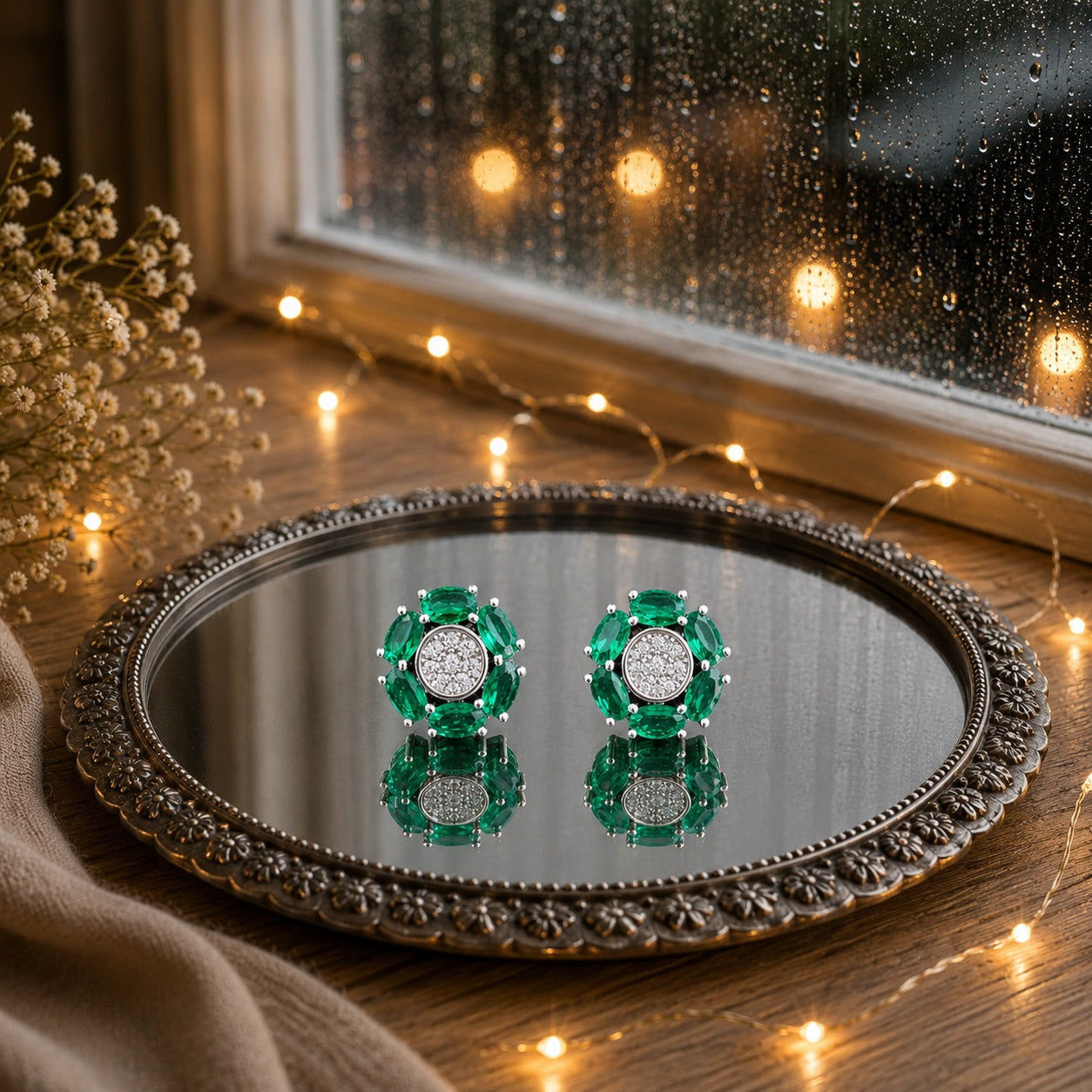 Floral crystal stud earrings with marquise-cut  green gemstone petals and a sparkling pavé center displayed on a decorative mirrored tray in a luxury jewelry photography setting.