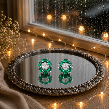 Floral crystal stud earrings with marquise-cut  green gemstone petals and a sparkling pavé center displayed on a decorative mirrored tray in a luxury jewelry photography setting.