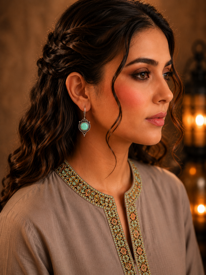 Woman wearing antique mint green round gemstone drop earrings with vintage detailing and embroidered taupe kurta, side profile jewellery photography.