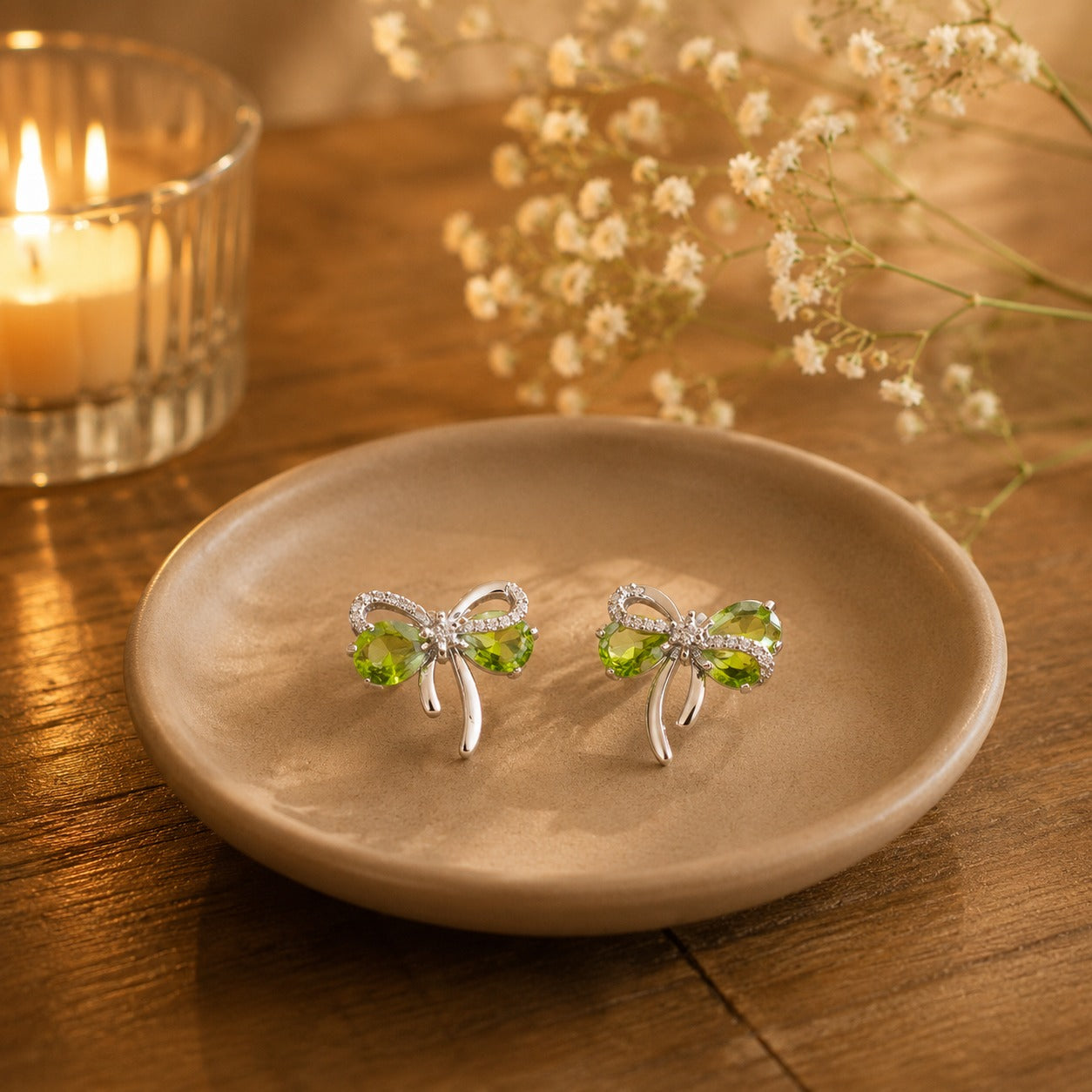 Olive green bow stud earrings on beige ceramic plate.