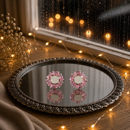 Floral crystal stud earrings with marquise-cut  pink gemstone petals and a sparkling pavé center displayed on a decorative mirrored tray in a luxury jewelry photography setting.