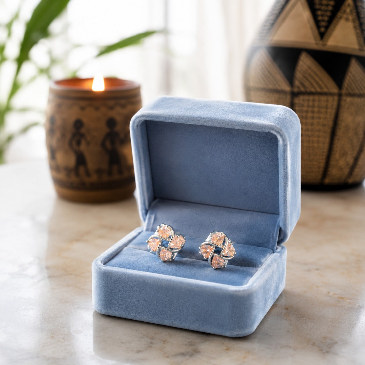 Crystal floral stud earrings displayed in a premium powder blue velvet jewellery box on a marble surface with a softly blurred luxury background.