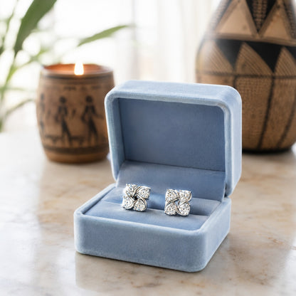 Crystal floral stud earrings displayed in a premium powder blue velvet jewellery box on a marble surface with a softly blurred luxury background.