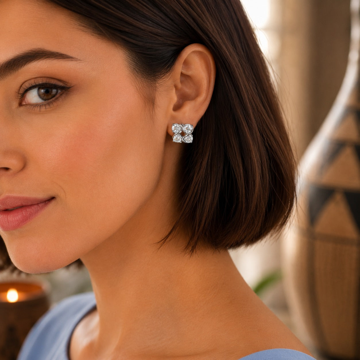 Close-up of a woman wearing four-petal crystal floral stud earrings with a polished silver or gold-tone finish.