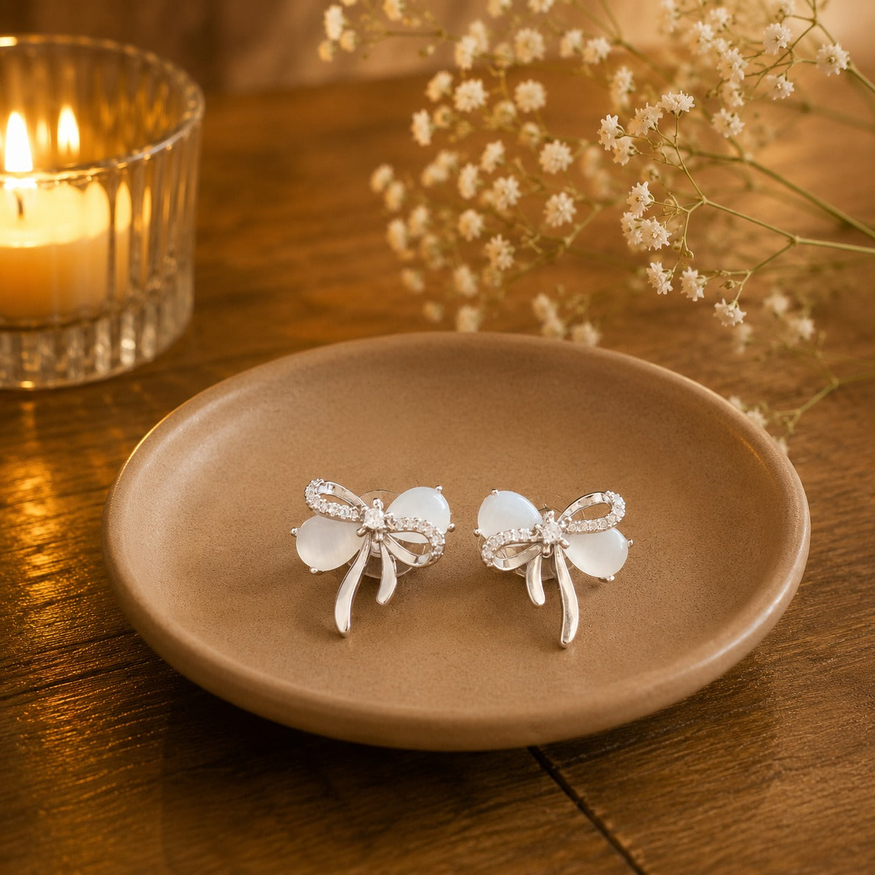 White opal bow stud earrings on beige ceramic plat